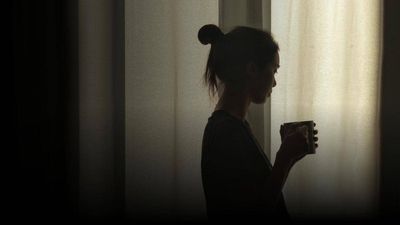 woman by window with mug in her hand